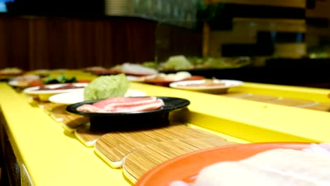 platos de comida fresca en el cinturón en un restaurante japonés