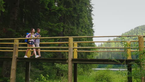 Ein-Paar-Touristen-Gehen-Vorsichtig-über-Eine-Brücke-über-Einen-Bergfluss-4k-Video