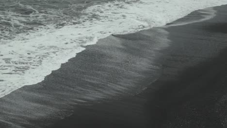 Antenne-Von-Wellen,-Die-An-Einem-Schwarzen-Sandstrand-In-Island-Zusammenbrechen