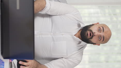 Vertical-video-of-Home-office-worker-man-looking-at-camera-confused.