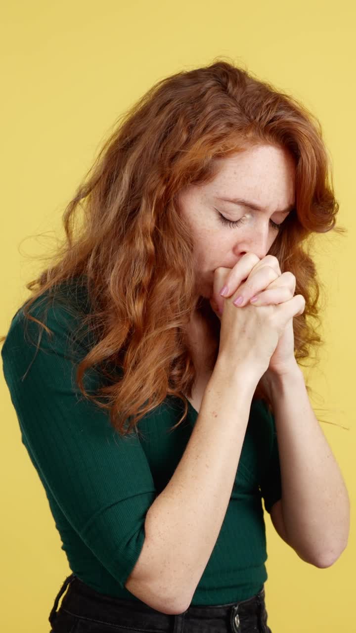 A red-haired woman with freckles expressing deep sadness, prayer, or contemplation