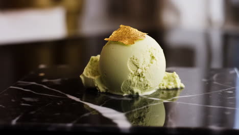 gourmet pistachio ice cream scoop with gold leaf on marble