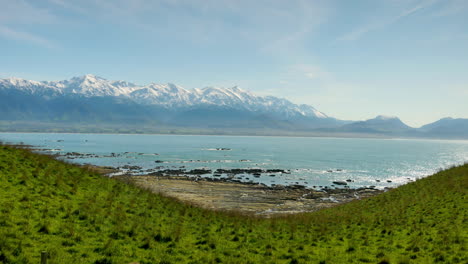 panorama shot of snow covered mountains of new zealand located in the near of tranquil ocean