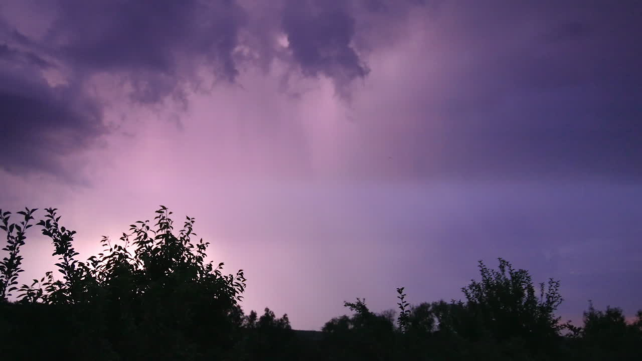 Thunderstorm raging in the rural countryside. Dark blue skies turning into purple from lightning. Night in the village.