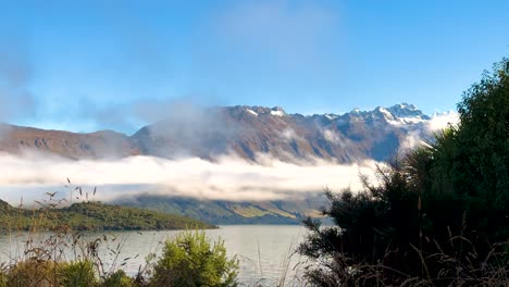 a tranquil scene of mountains and lake wakatipu with drifting clouds, captured in bright daylight