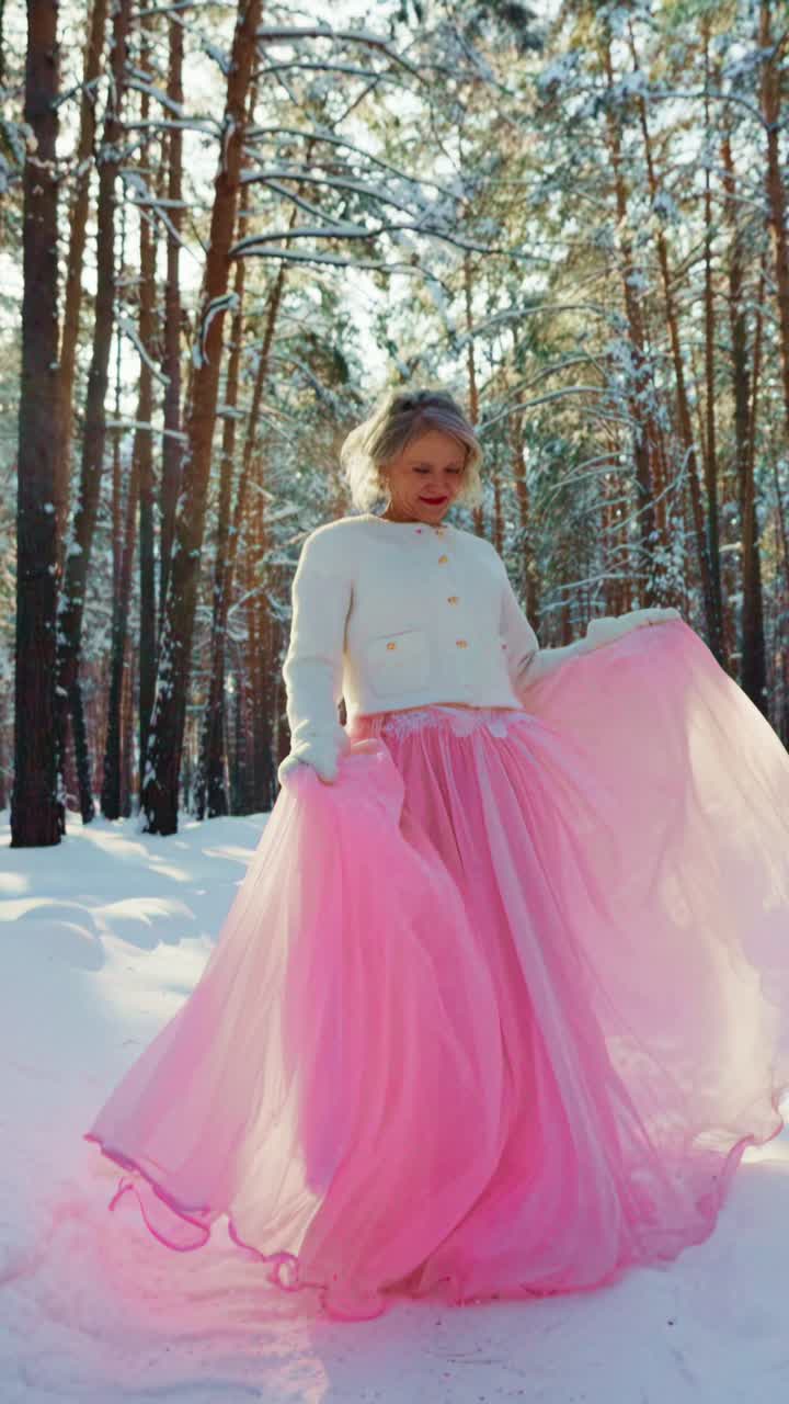 Donna gioiosa in abito rosa che volteggia in una foresta invernale innevata