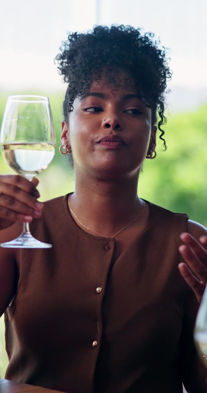 Young Woman Drinking White Wine and Talking at a Social Gathering