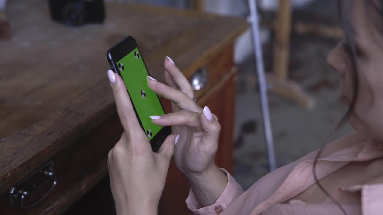 mujer sosteniendo un teléfono inteligente con una pantalla verde