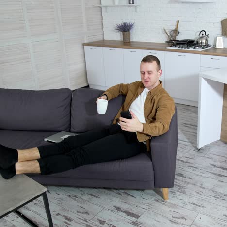 man using cellphone at home. young man relaxing on couch at home and using mobile phone