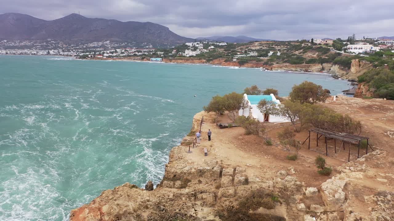 The drone retreats from the mountain, revealing a panorama of the city and the rugged cliffs and peaks.