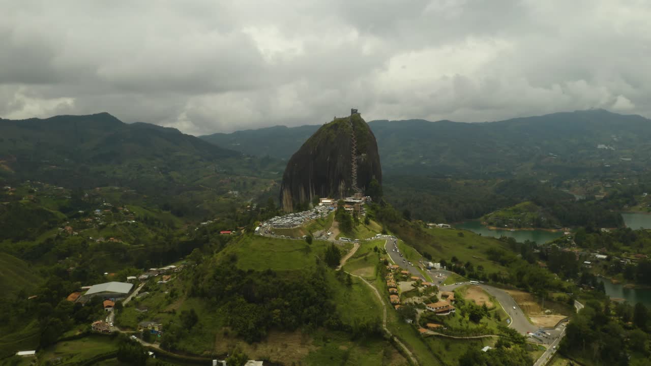 Drone se afastando da Rocha de Guatapé revelando lagos e campos agrícolas abaixo