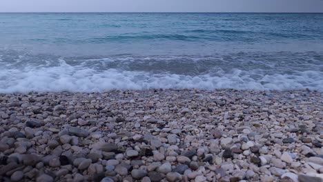 Quiet-sea-after-the-storm,-waves-washing-pebbles-beach-on-a-cold-day-during-the-autumn-in-Mediterranean