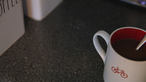 stirring milk into coffee with a spoon in a red and white bicycle mug