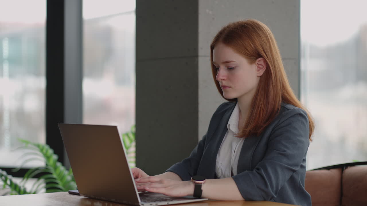 Pretty student woman using laptop in outdoors cafe while having cup of coffee. Cheerful woman working at cafe on laptop. Businesswoman working during layover at modern airport.