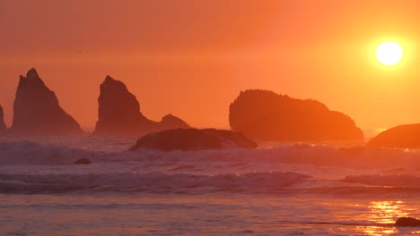 a slow-motion shot of a large wave crashing in red light with the sun orb setting behind it