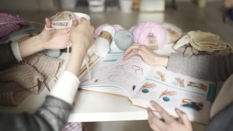 two woman friends using book with knitting pattern. knitting needles