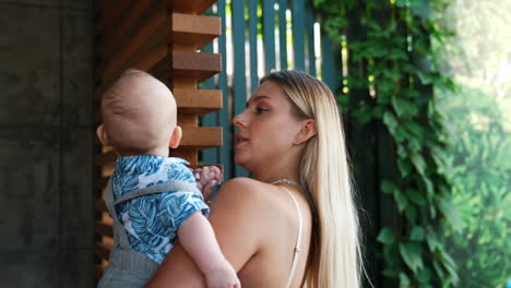 beautiful blonde lady holding a baby in hands. mother with her infant child outdoors in summer.
