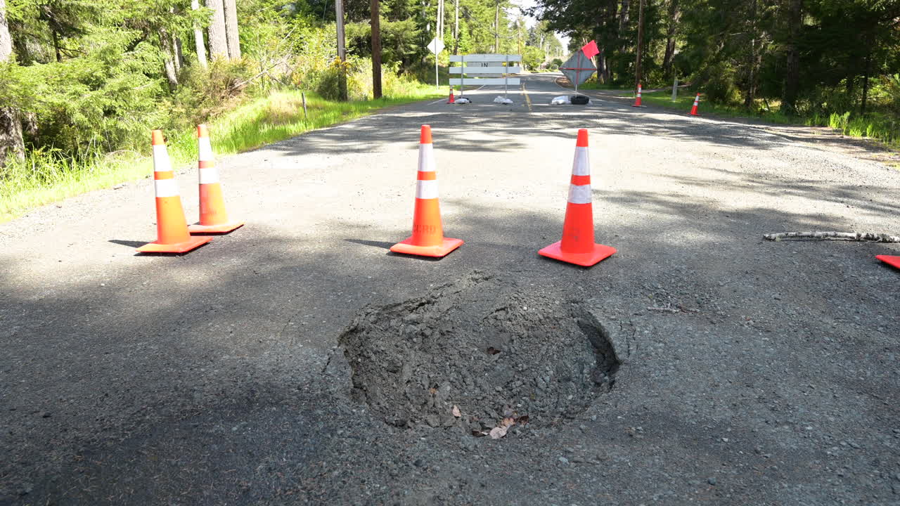 Traffic cones at a hole in the street from a broken culvert. Road closure in Oregon.