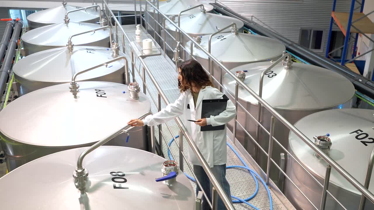 Scientist Inspecting Stainless Steel Tanks in Industrial Setting