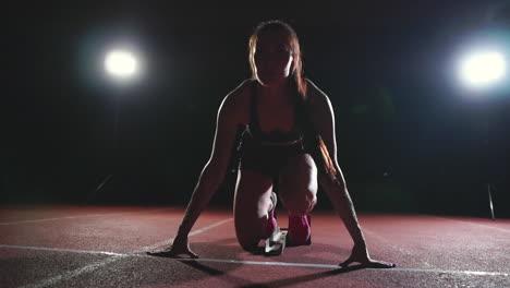 atleta femenina en un fondo oscuro para correr el sprint de la almohadilla de cross country en la cinta de correr en un fondo oscuro