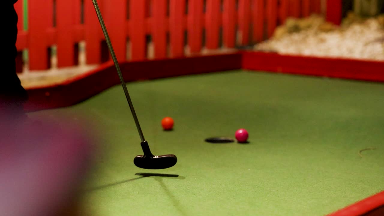 A colorful miniature golf scene with a putter missing the ball. Bright lighting and playful atmosphere enhance the fun environment
