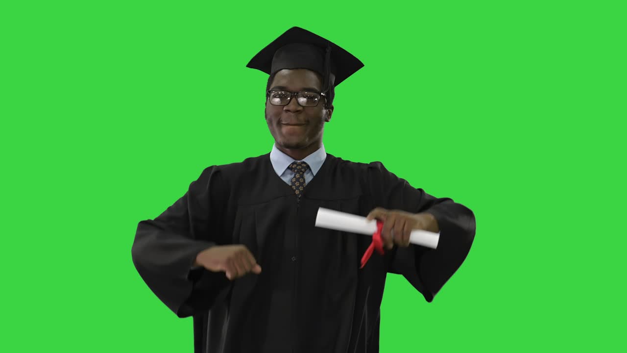 Excited african american male student in graduation robe dancing with his diploma moving towards camera on a Green Screen, Chroma Key