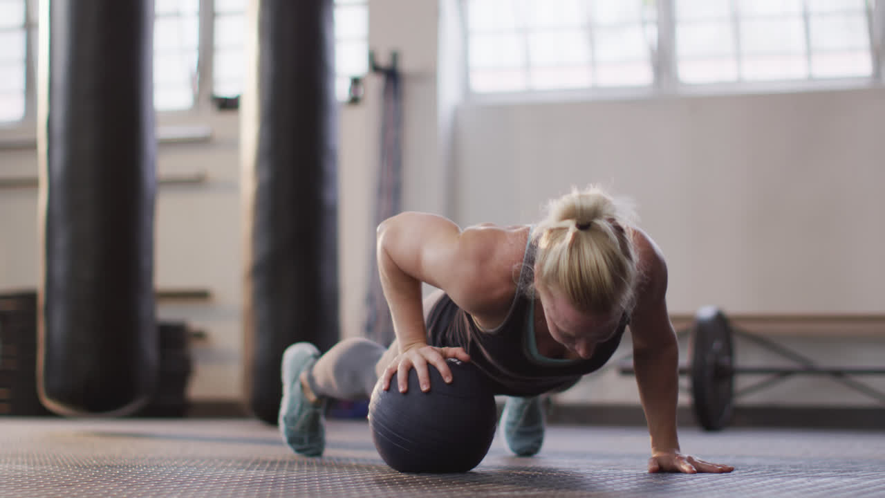 mujer caucásica en forma trabajando con la pelota de medicina en el gimnasio