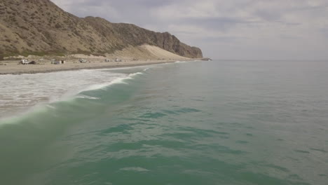volar sobre las olas rodando hacia la costa hacia la costa de california con colinas