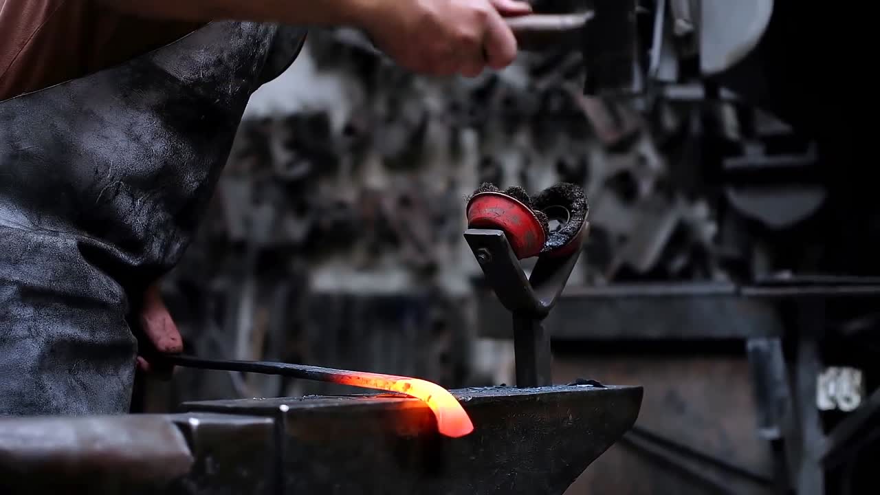 Blacksmith shaping the molten metal with hammer 4k