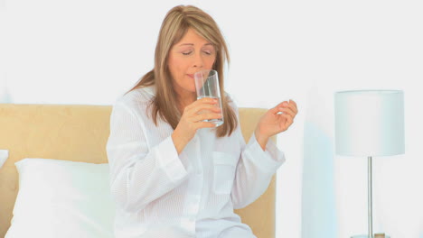 una mujer madura enferma tomando pastillas
