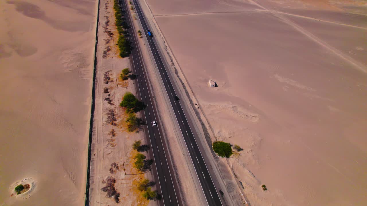 Cinematic aerial semi orbit following a car on the Peruvian desert highway near the coast with ocean in the background