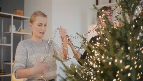 friends decorating xmas tree with illuminated lights