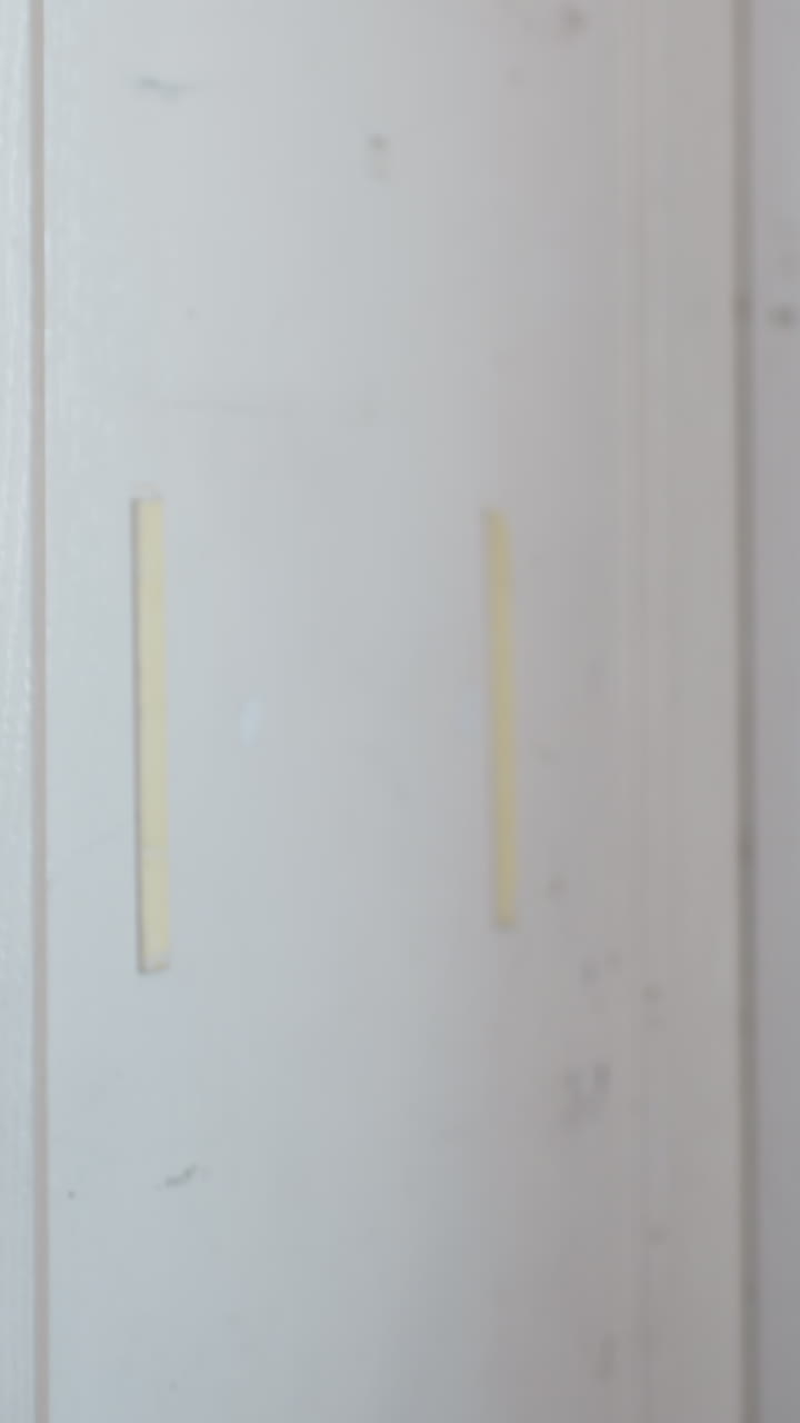 Panel de puerta desgastado con restos de pintura y marcas de roce, estudio de primer plano de la superficie que muestra vetas de madera astilladas y residuos de adhesivo, bordes sutiles visibles en el marco, fondo de estudio neutro, textura