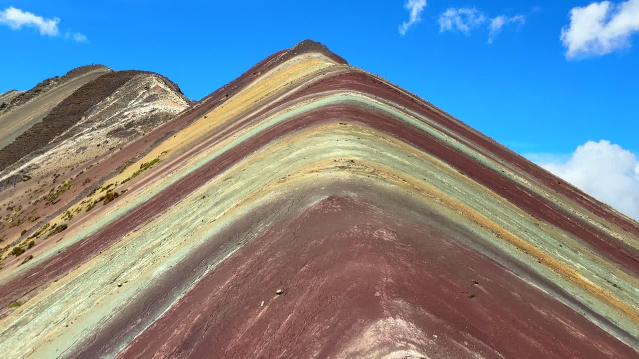 Primo piano della Montagna Arcobaleno Vinicunca, Perù, al mattino con cielo azzurro e nuvole. Montaña de Siete Colores Palccoyo nelle Ande Peruviane, con la Valle Rossa e le colline striate di sette colori nella Regione di Cusco. Vista panoramica del paesaggio naturale.