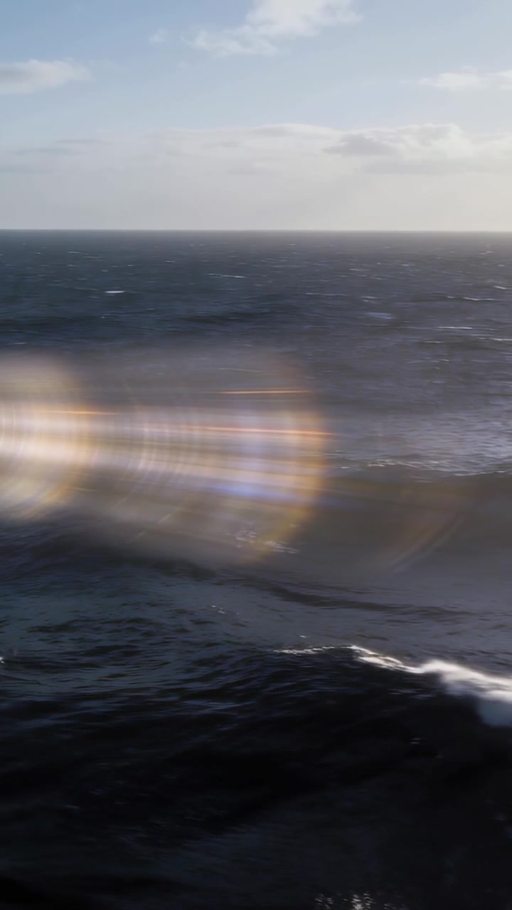 Vertical video: Showing ocean waves churning at horizon, wind driving waves, sunlight causing flare