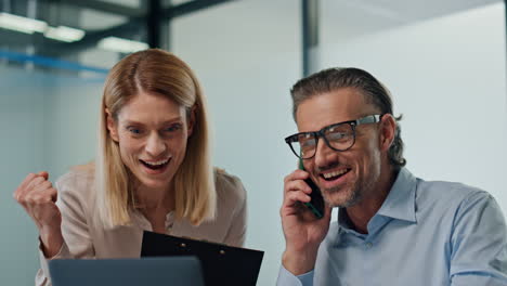 excitados hombres de negocios alegrándose de la oficina moderna. excitados colegas dando cinco