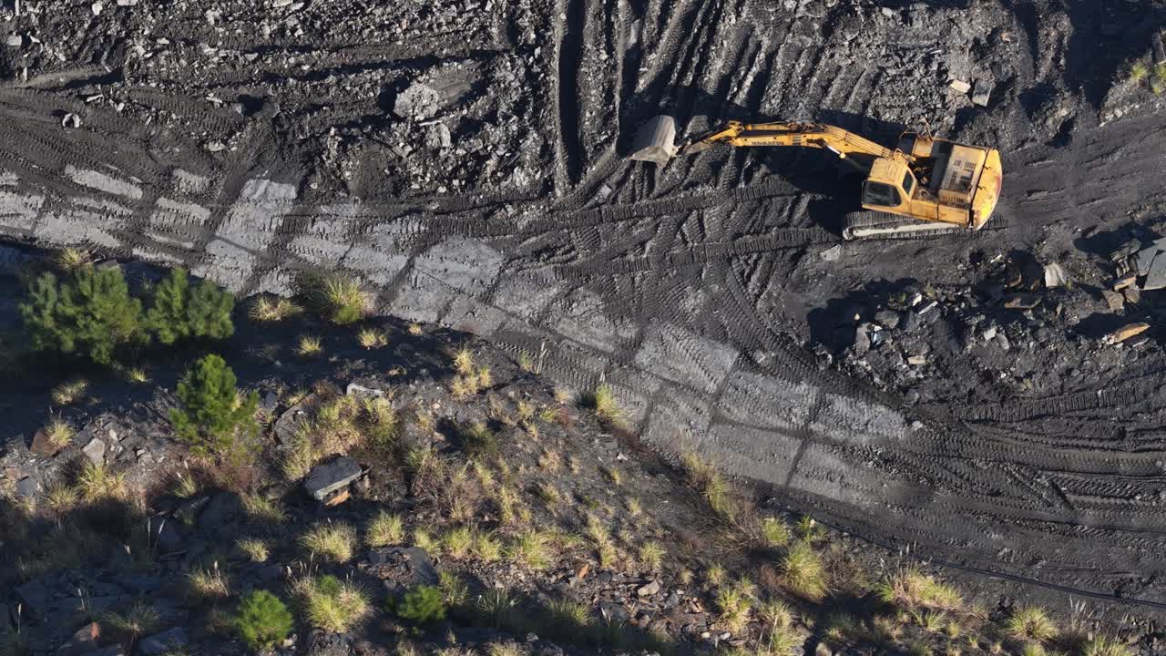 Yellow excavator on a rock mining facility