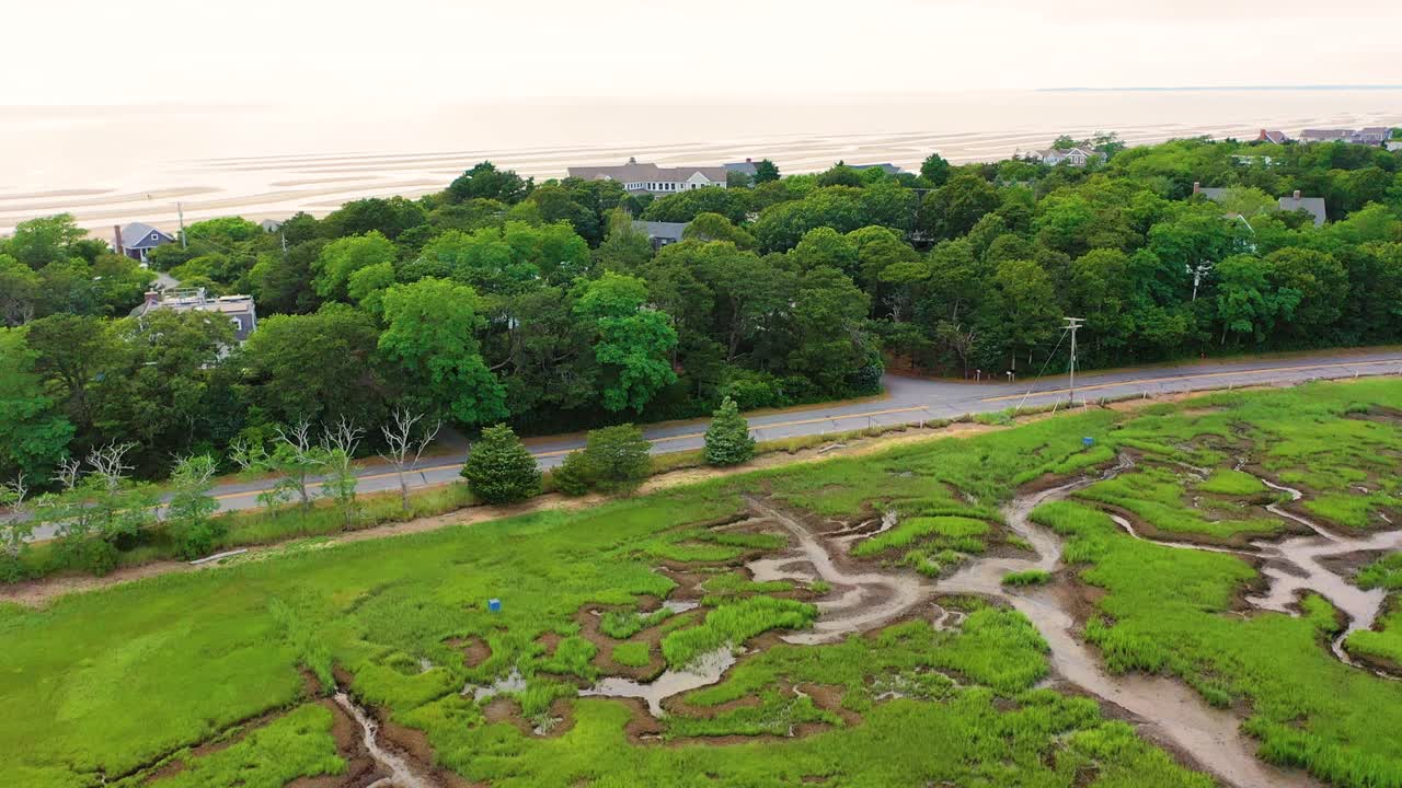Aerial video of wetlands highlights tidal flats, reflective pools, and grassy waterways stretching outward, with natural designs only visible through the sweeping perspective from above