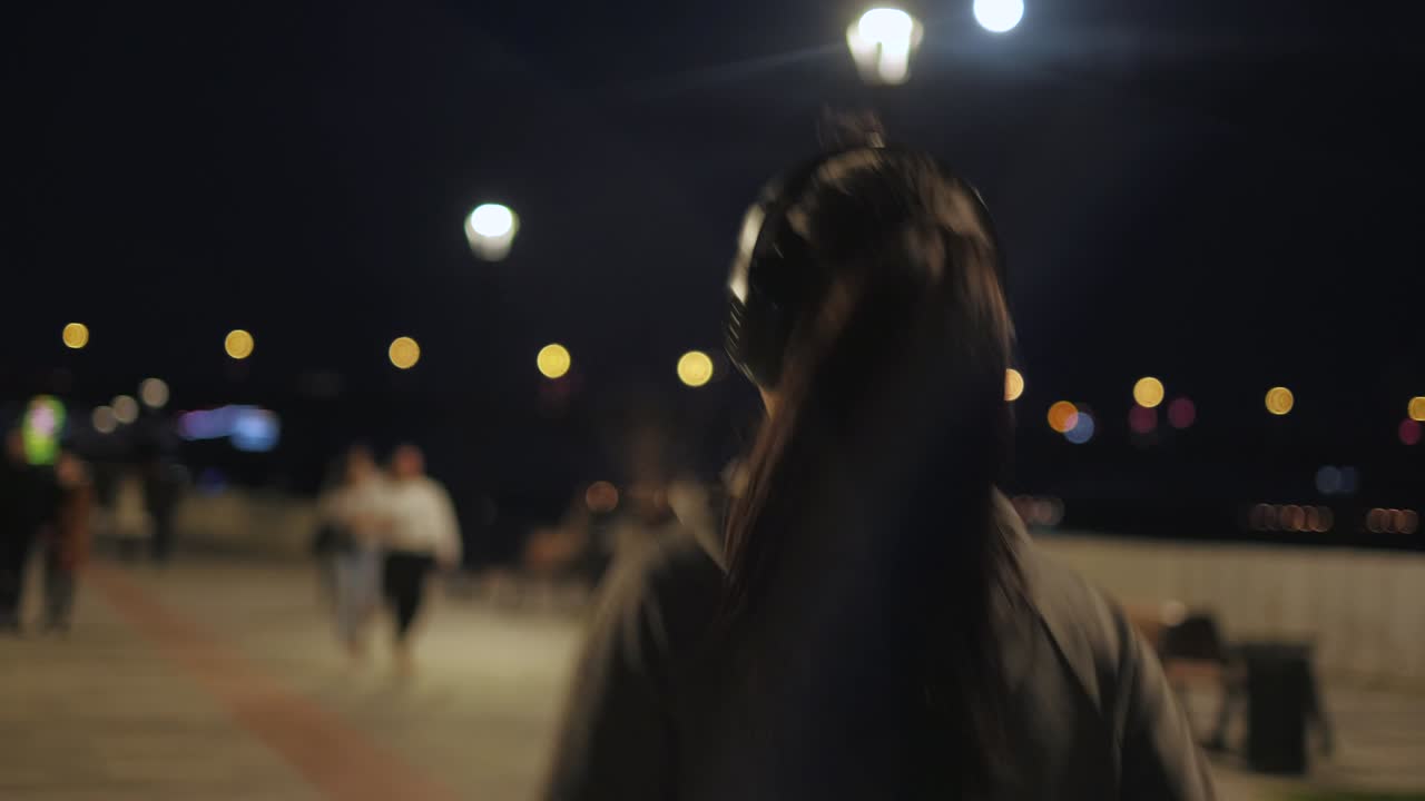 la chica corre por la ciudad nocturna y escucha música con auriculares. deportes al aire libre. correr de noche