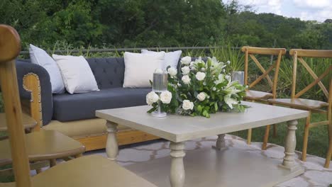 a wooden table with a vase of white flowers and a couple of chairs and furniture around it