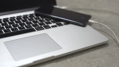 hand-plugging-the-charger-into-cell-phone-against-laptop-computer