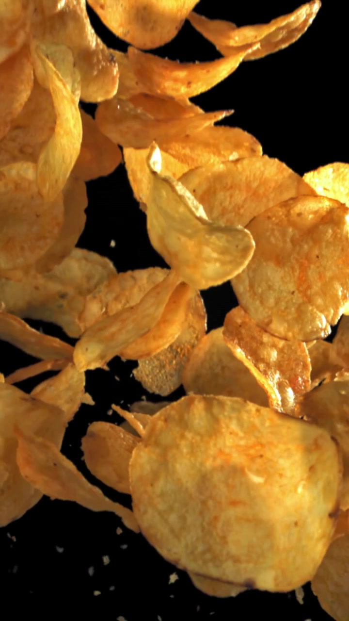 Crispy Golden Potato Chips Falling in Slow Motion on Black Background
