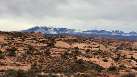 the desert in moab, utah with a backdrop of snow capped mountains making it a perfect picturesque panaromic view