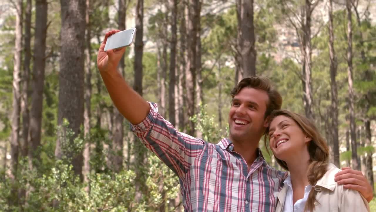 pareja sonriente en una caminata tomando una selfie