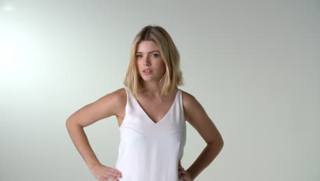 mujer rubia joven poniendo las manos en las caderas sonriendo a la cámara