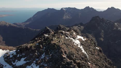 Aufschlussreiche-Drohnenaufnahme-Eines-Wanderers,-Der-Die-Aussicht-Auf-Den-Cuillin-Mountain-Ridge-In-Schottland-Genießt