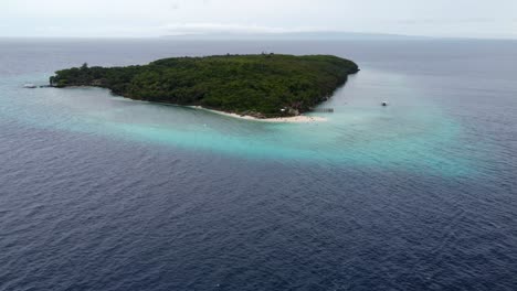 Aerial-drone-view-of-the-Sumilon-island,-with-a-tourist-filipino-banca-Boat-passing-by,-a-small-island-in-open-sea-with-white-sandbar-beach-off-the-shore-of-oslob-in-Cebu-philippines