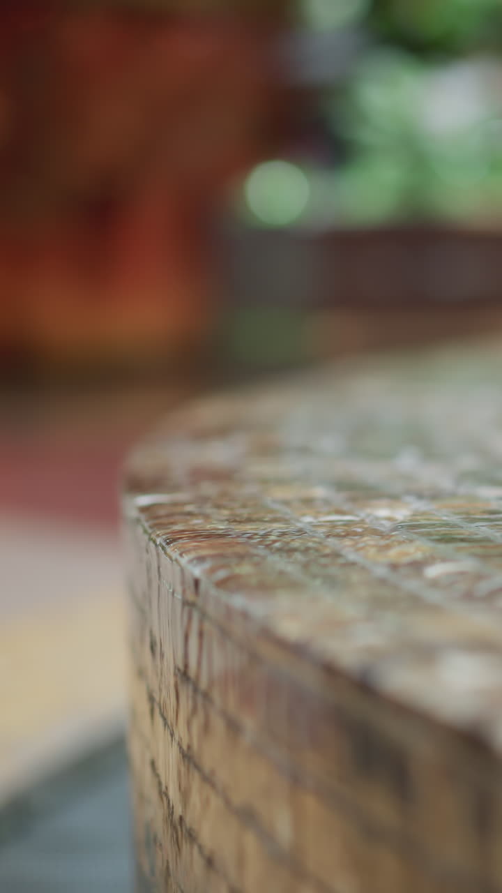 primer plano de agua que fluye por el borde de la fuente de azulejos de mosaico con un fondo suavemente borroso con luz ambiental y toques de vegetación