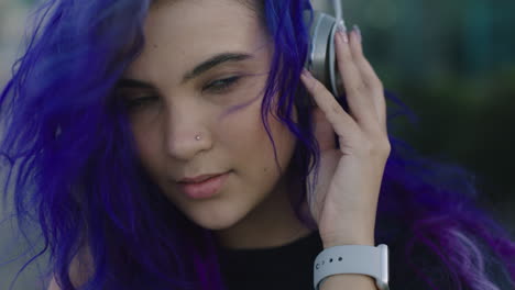 close up portrait beautiful young woman wearing headphones listening to music smiling happy enjoying urban lifestyle wind blowing purple hair