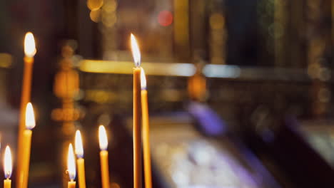 tranquil atmosphere of light candles burning brightly in the blurred background. wax candles are glowing in church.